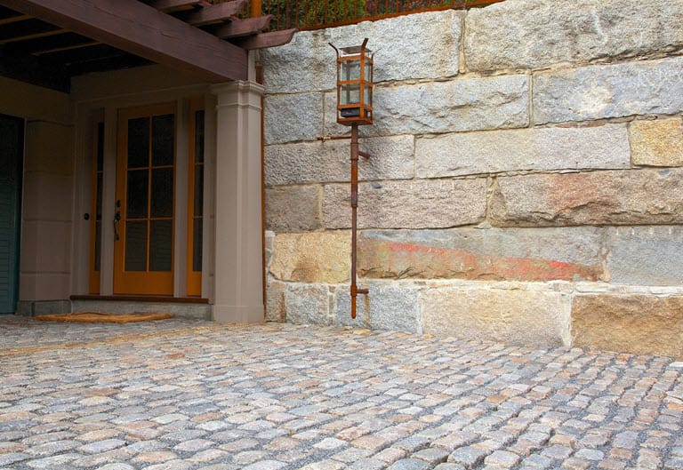Reclaimed bridge block retaining wall and cobblestone driveway