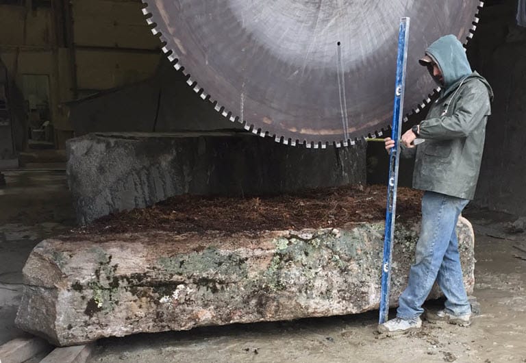 Man with giant saw cutting stone block