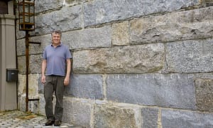 Gavin Johnston in front of reclaimed granite bridge block retaining wall