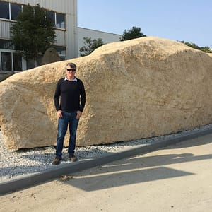 Gavin Johnston in front of giant boulder in China