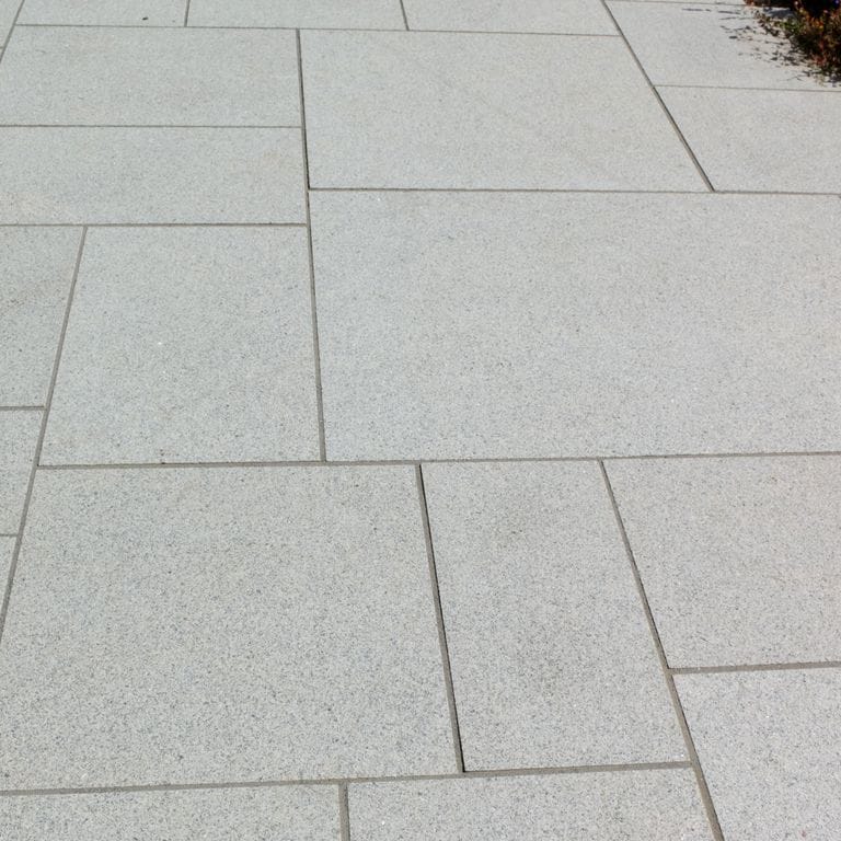 Application image for Granite - Cape Neddick Clear. The image shows this material being used in a patio pavers application. Dominant colors shown are beige and gray. The color mix creates a cool feeling. Fine speckled color pattern.