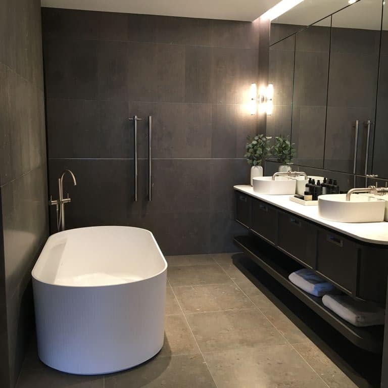 Feature image for Fossil Gray Limestone. The image shows this material being used in an interior floor application. The dominant color shown is gray; with beige, blue, pink, purple, white and cream secondaries. The color mix creates a warm feeling. Random color pattern. Contains mineral inclusions.
