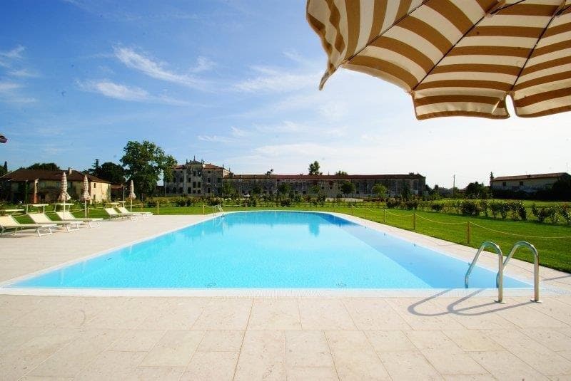 Application image for Grolla Rosato Limestone. The image shows this material being used in a pool deck pavers application. The surface finish shown is flamed. Dominant colors shown are beige and tan; with a cream secondary. The color mix creates a warm feeling. Cloudy color pattern.