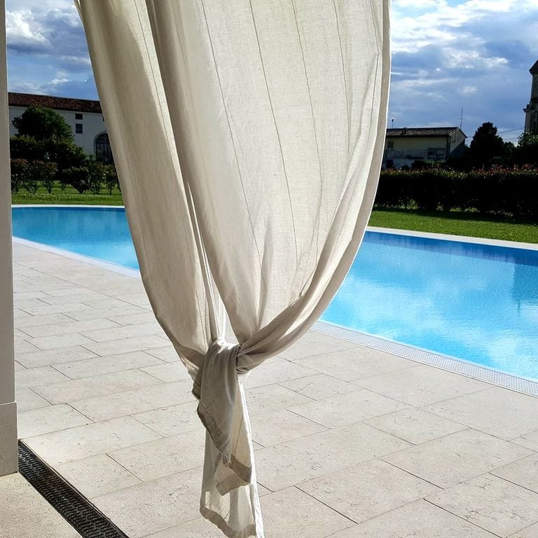 Application image for Grolla Rosato Limestone. The image shows this material being used in a pool deck pavers application. The surface finish shown is flamed. Dominant colors shown are beige, gray and cream; with pink, purple, white and tan secondaries. The color mix creates a warm feeling. Cloudy color pattern.