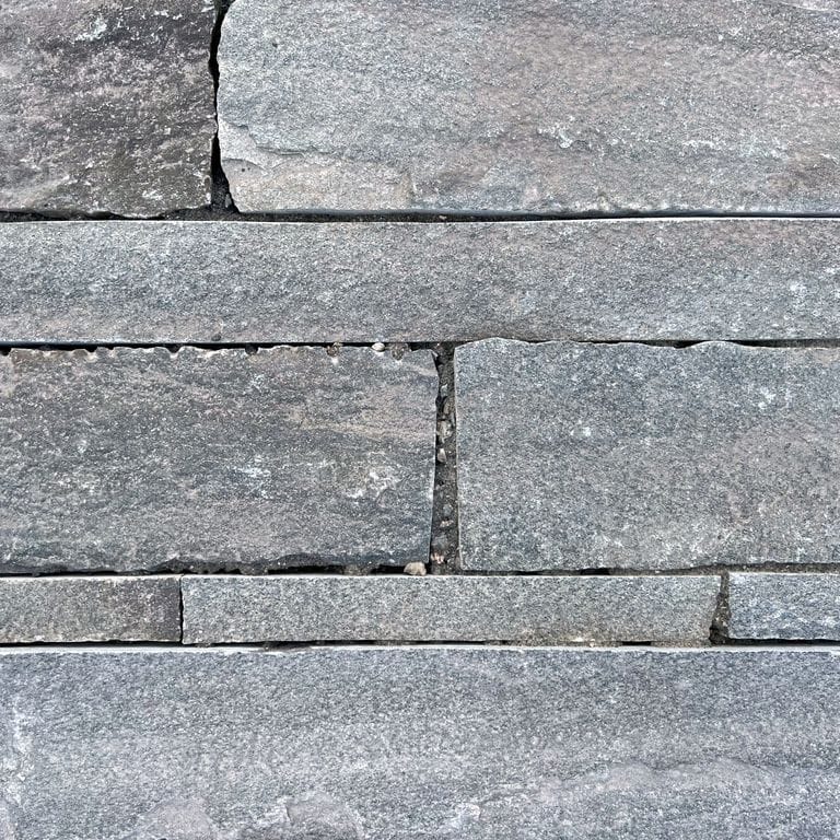 Best close-up image for Reclaimed Quartzite Plank Pavers - Blue/Gray. The image shows this material being used in a patio pavers application. The surface finish shown is a combination of split-face with flat plane, weathered and worn. Dominant colors shown are beige, blue, brown and gray; with green, orange/rust, purple, white, tan and cream secondaries. Regular, linear and blotched color patterns. Contains some mica.