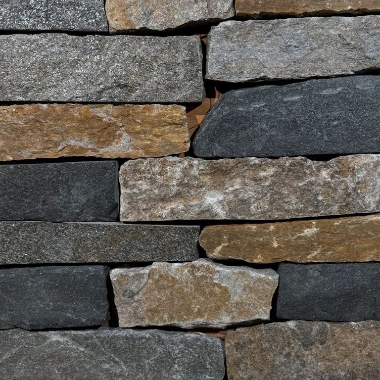 Color/Finish variation image for Vermont Granite Blend. The surface finish shown is split-face. Dominant colors shown are black, brown, gray and tan. The color mix creates a warm feeling. Regular, random and coarse speckled color patterns.