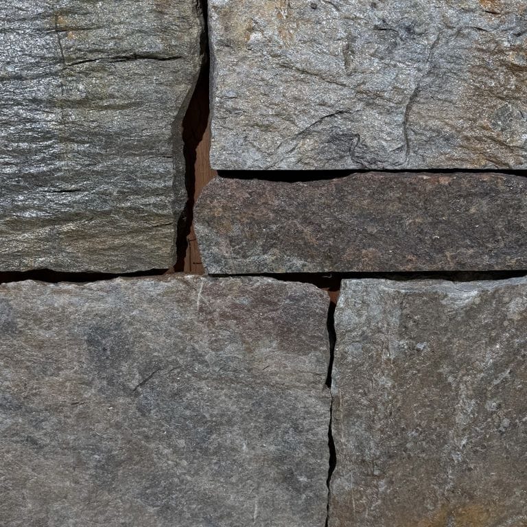 Color/Finish variation image for Quaker Hill Granite. The surface finish shown is split-face. The dominant color shown is gray. The color mix creates a warm feeling.