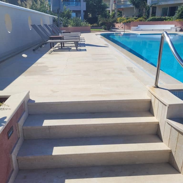 Application image for Limestone - Moon Beige. The image shows this material being used for pool coping, landings, treads and pool deck pavers. Dominant colors shown are beige, tan and cream. The color mix creates a warm feeling.