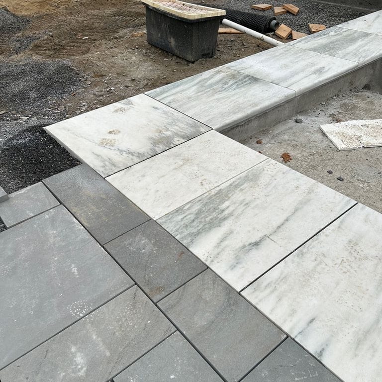 Application image for Marble - White Cloud. The image shows this material being used in a pool coping application. Dominant colors shown are gray and white. The color mix creates a cool feeling.