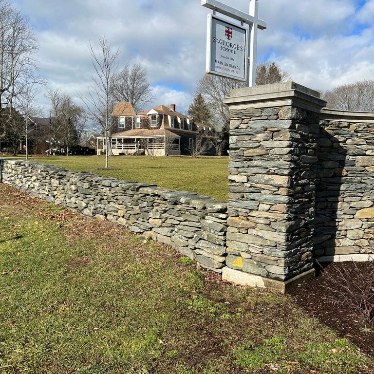 Application image for New England Fieldstone Flats. The image shows this material being used for landscape wallstone and thin veneer. The surface finish shown is weathered. Dominant colors shown are gray and tan. The color mix creates a warm feeling.