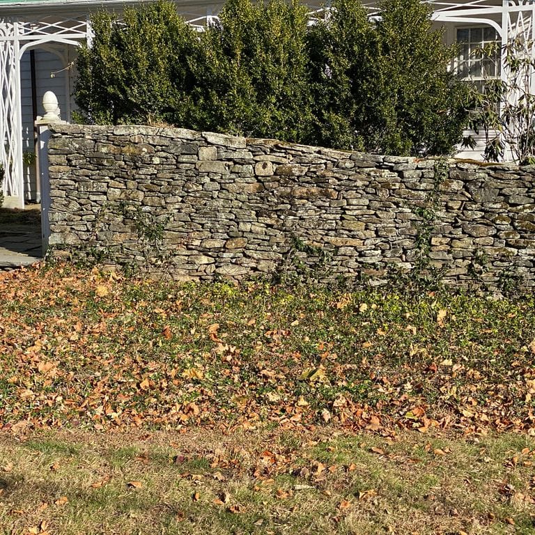 Application image for Fieldstone - New England Flats. The image shows this material being used in a landscape wallstone application. The surface finish shown is weathered. The dominant color shown is brown. The color mix creates a warm feeling.