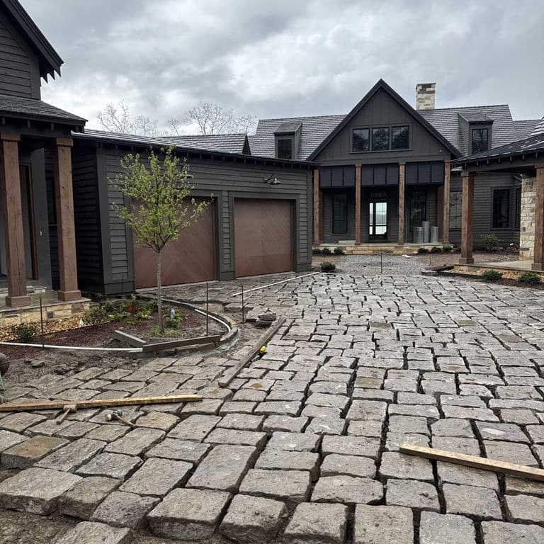 Application image for Reclaimed New England Bridge Squares. The image shows this material being used in a driveway pavers application. The surface finish shown is . The dominant color shown is gray.