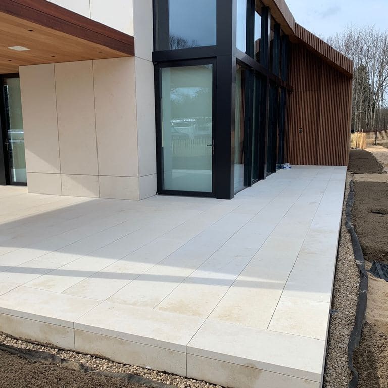 Application image for Buff Limestone. The image shows this material being used in a patio pavers application. The surface finish shown is sand blasted. Dominant colors shown are beige and tan. The color mix creates a warm feeling.