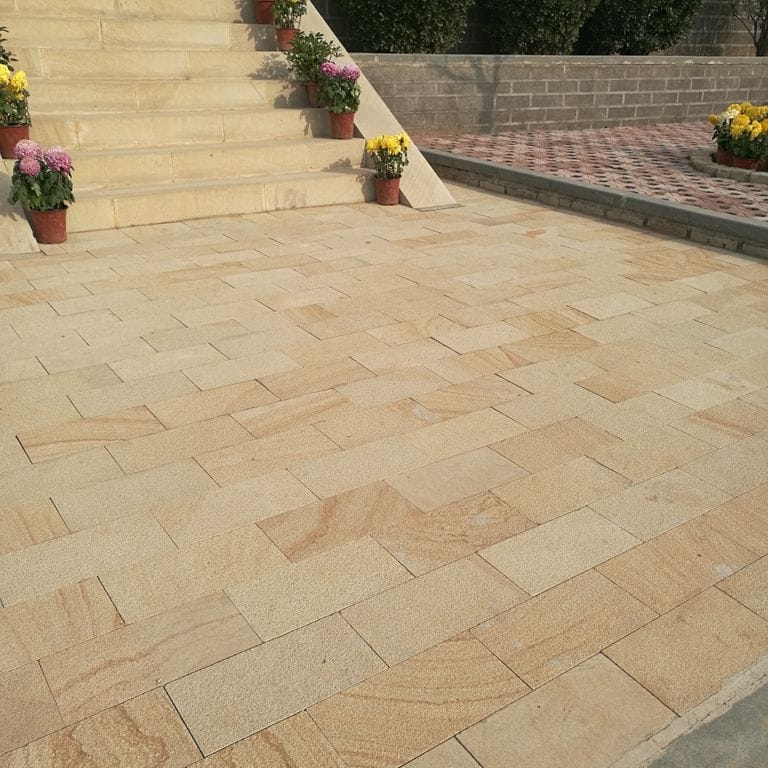 Application image for Beige Vein Cut Granite. The image shows this material being used in a patio pavers application. Dominant colors shown are orange/rust and tan. The color mix creates a warm feeling.