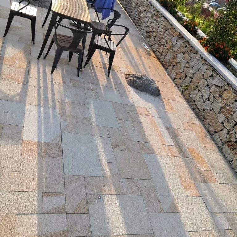 Application image for Beige Vein Cut Granite. The image shows this material being used in a patio pavers application. Dominant colors shown are orange/rust and tan. The color mix creates a warm feeling.