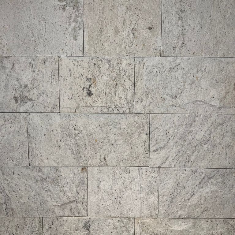 Best close-up image for Strata Snow Gneiss. The image shows this material being used in an interior cladding application. The surface finish shown is split-face. Dominant colors shown are gray and white. The color mix creates a warm feeling.