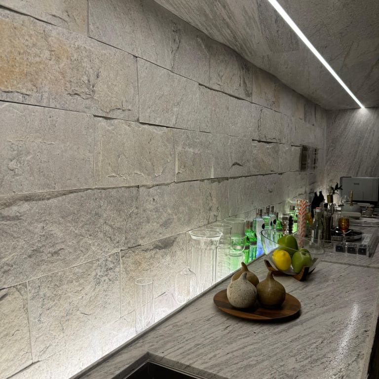 Feature image for Strata Snow Gneiss. The image shows this material being used in an interior cladding application. The surface finish shown is split-face. The dominant color shown is white.