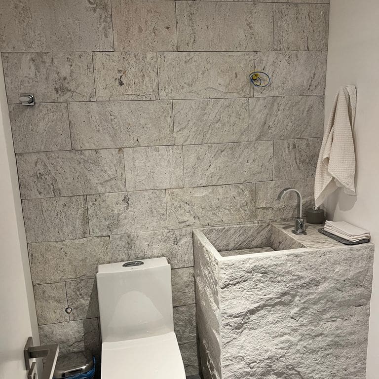 Application image for Strata Snow Gneiss. The image shows this material being used in an interior cladding application. The surface finish shown is split-face. The dominant color shown is white.