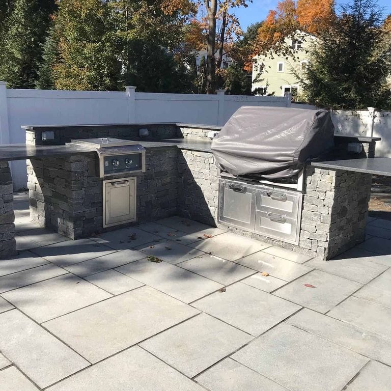 Application image for Oyster Bay Granite. The image shows this material being used in a thin veneer application. The surface finish shown is split-face. The dominant color shown is gray. The color mix creates a cool feeling.