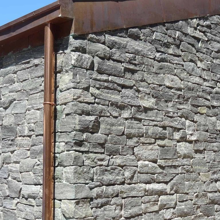 Application image for Greenwich Gray Granite. The image shows this material being used in a thin veneer application. The surface finish shown is split-face. The dominant color shown is gray. The color mix creates a cool feeling.