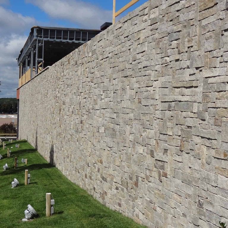 Application image for New England Tan Granite. The image shows this material being used in a thin veneer application. The surface finish shown is split-face. Dominant colors shown are gray and tan. The color mix creates a warm feeling.