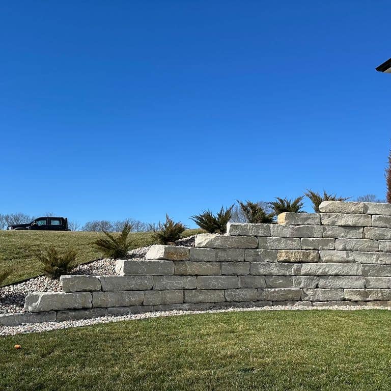 Application image for Great Plains Limestone - Gray. The image shows this material being used for landscape wallstone and retaining wall. The surface finish shown is split-face. The dominant color shown is gray. The color mix creates a warm feeling.