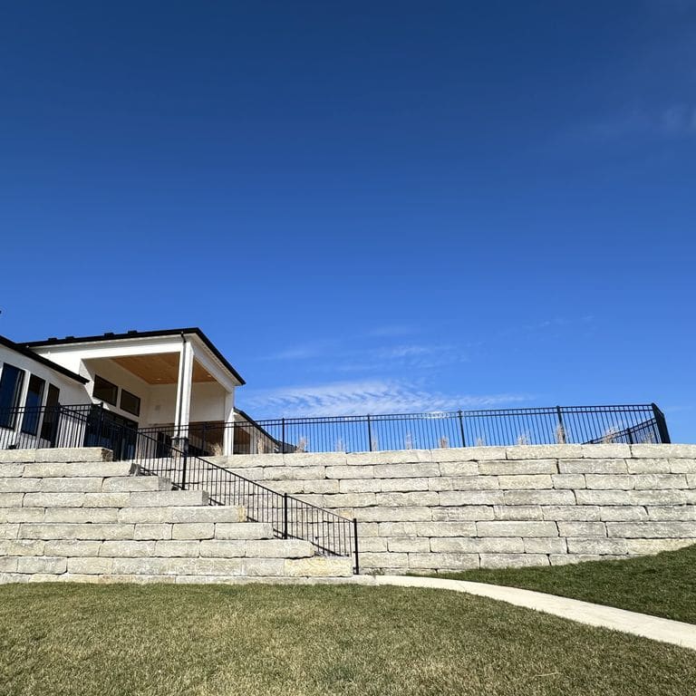 Application image for Great Plains Limestone - Gray. The image shows this material being used for landscape wallstone and retaining wall. The surface finish shown is split-face. The dominant color shown is gray. The color mix creates a warm feeling.