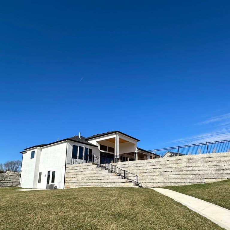 Application image for Great Plains Limestone - Gray. The image shows this material being used for landscape wallstone and retaining wall. The surface finish shown is split-face. The dominant color shown is gray.