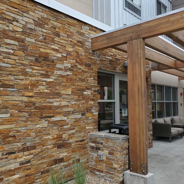 Feature image for Golden Oakley Stone. The image shows this material being used in a full bed veneer application. The surface finish shown is split-face. Dominant colors shown are brown and orange/rust. The color mix creates a warm feeling.