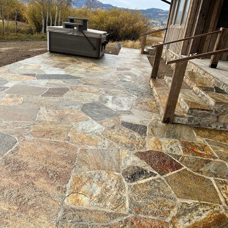 Application image for Golden Oakley Stone. The image shows this material being used in a patio pavers application. The surface finish shown is natural cleft. Dominant colors shown are brown, orange/rust and tan. The color mix creates a warm feeling.
