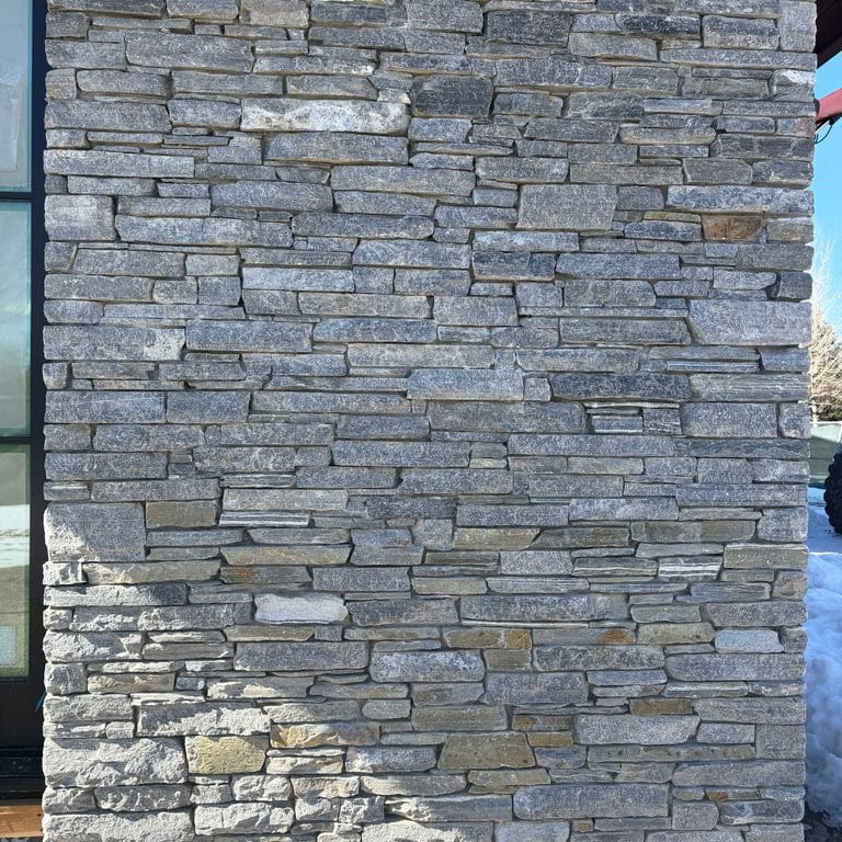 Application image for Charcoal Oakley Stone. The image shows this material being used in a full bed veneer application. The surface finish shown is split-face. The dominant color shown is gray. The color mix creates a cool feeling.