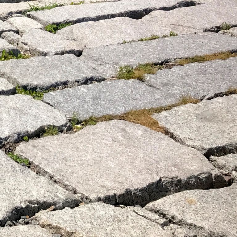 Best close-up image for Reclaimed Granite Block. The surface finish shown is a combination of rockfaced, split-face, weathered and worn. Dominant colors shown are beige and gray; with brown, orange/rust, pink, purple, white, tan and cream secondaries. The color mix creates a warm feeling. Regular, fine speckled and speckled color patterns.