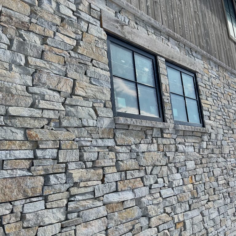 Best close-up image for Oakley Stone - Birch Silver. The image shows this material being used in a full bed veneer application. The surface finish shown is split-face. Dominant colors shown are gray and cream. The color mix creates a cool feeling.