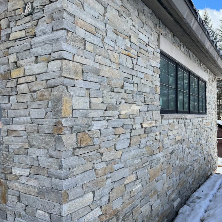 Feature image for Oakley Stone - Birch Silver. The image shows this material being used in a full bed veneer application. The surface finish shown is split-face. Dominant colors shown are beige and gray. The color mix creates a cool feeling.