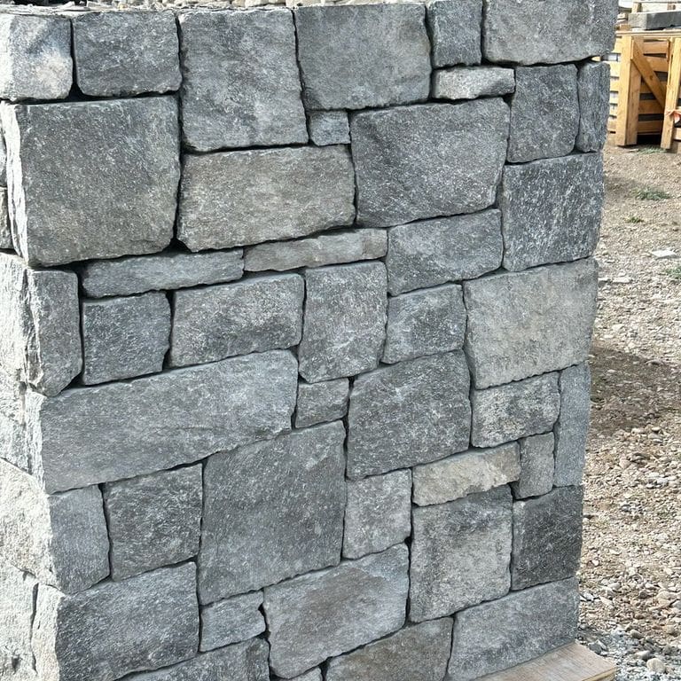 Application image for Rocky Mountain Granite. The image shows this material being used in a full bed veneer application. The surface finish shown is split-face. The dominant color shown is gray.