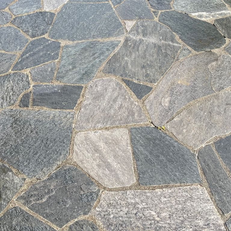 Best close-up image for Cowboy Coffee Quartzite. The image shows this material being used in a patio pavers application. The surface finish shown is natural cleft. The dominant color shown is gray. The color mix creates a cool feeling.