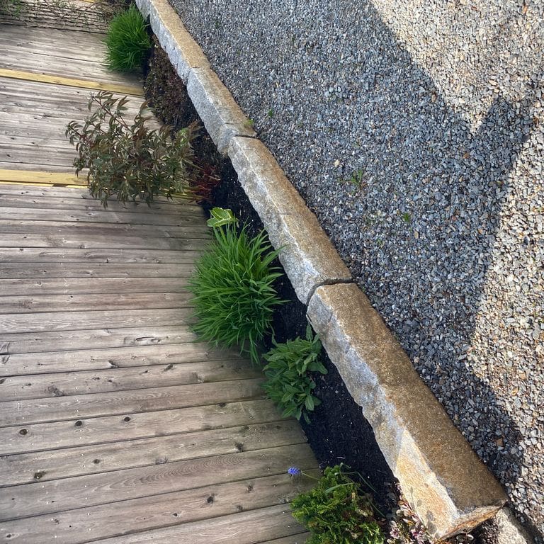 Application image for Reclaimed Granite Curbstone - Junior. The image shows this material being used in a landscape curbing &amp; edging application. This is a building and landscape stone for indoor and outdoor commercial and residential applications. Suitable for general use, freeze-thaw conditions, low heat absorption surfaces, high traffic areas and low slipperiness surfaces situations. Moderate to higher on the price spectrum.