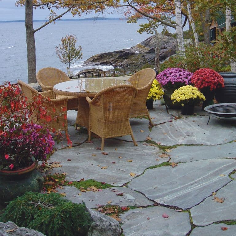 Feature image for Granite - Mystic Mountain- Flamed. The image shows this material being used in a patio pavers application. Dominant colors shown are blue and gray; with green, purple and white secondaries. The color mix creates a cool feeling. Linear, streaked and random color patterns.