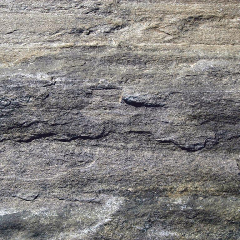 Close-up image for Mystic Mountain - Natural. The surface finish shown is weathered. The dominant color shown is gray; with beige, black, blue, brown, green, orange/rust, purple, white and tan secondaries. Exhibits "movement". Blotched and linear color patterns.