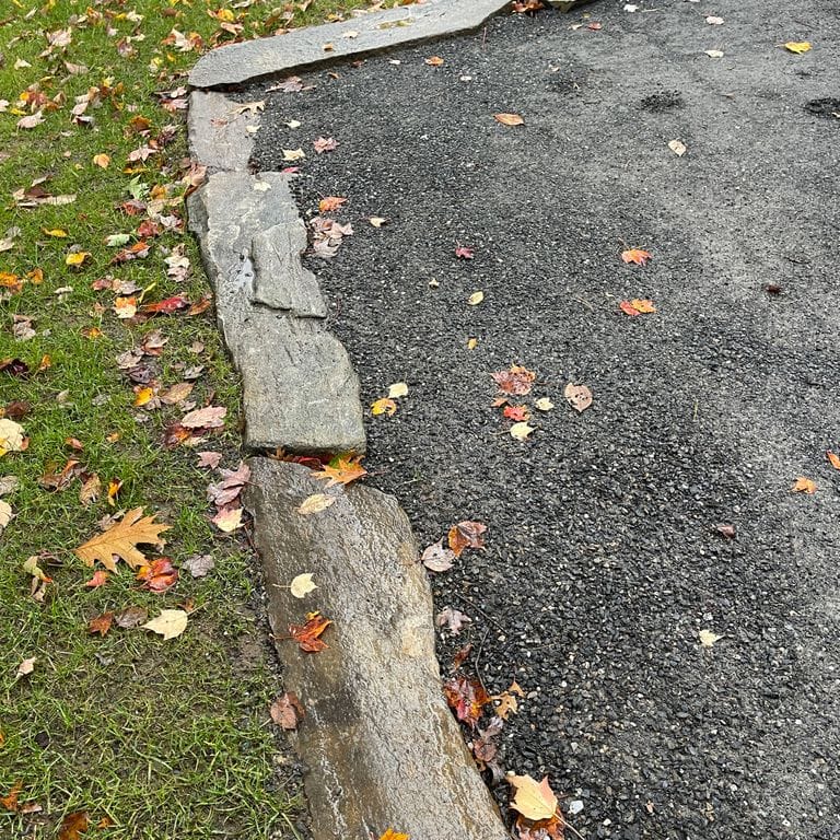 Application image for Mystic Mountain - Natural. The image shows this material being used in a landscape curbing &amp; edging application. The surface finish shown is natural. The dominant color shown is gray; with beige, white and tan secondaries. The color mix creates a cool feeling. Regular color pattern.