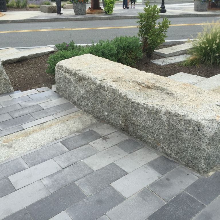 Application image for Reclaimed Granite Bridge Blocks. The image shows this material being used in a seating &amp; benches application. The surface finish shown is a combination of weathered and worn. The dominant color shown is gray; with a tan secondary. The color mix creates a warm feeling.