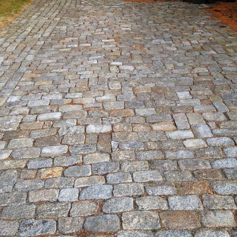 Application image for Granite - Reclaimed New England Cobblestones. The image shows this material being used in a driveway pavers application.