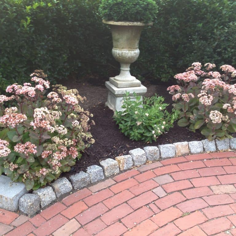 Application image for Reclaimed New England Granite Cobblestones - Medium. The image shows this material being used in a landscape curbing &amp; edging application. This is a landscape stone for outdoor commercial and residential applications. Suitable for general use, freeze-thaw conditions, low heat absorption surfaces, high traffic areas and low slipperiness surfaces situations. Moderate to higher on the price spectrum.