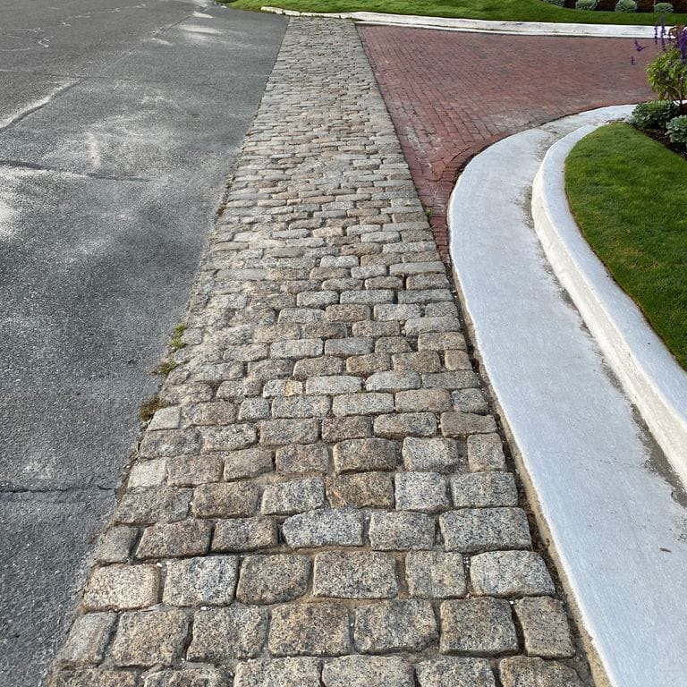 The image shows this material being used in a driveway aprons application. The dominant color shown is gray; with beige, brown, white, tan and cream secondaries. The color mix creates a warm feeling. Regular color pattern.
