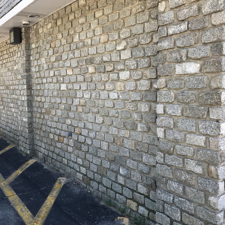 Application image for Reclaimed New England Granite Cobblestones - Medium. The image shows this material being used in a full bed veneer application. The surface finish shown is a combination of weathered and worn. The dominant color shown is gray; with a white secondary. The color mix creates a cool feeling. Fine speckled and speckled color patterns.