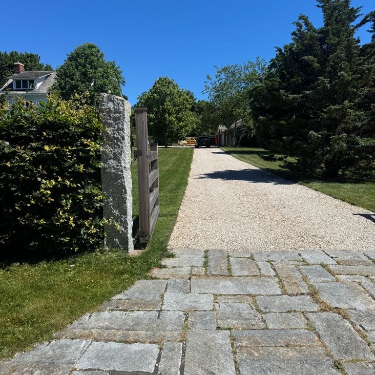 Application image for Reclaimed New England Granite Super Jumbo Cobblestones. The image shows this material being used in a driveway aprons application. The surface finish shown is . The dominant color shown is gray. The color mix creates a warm feeling.