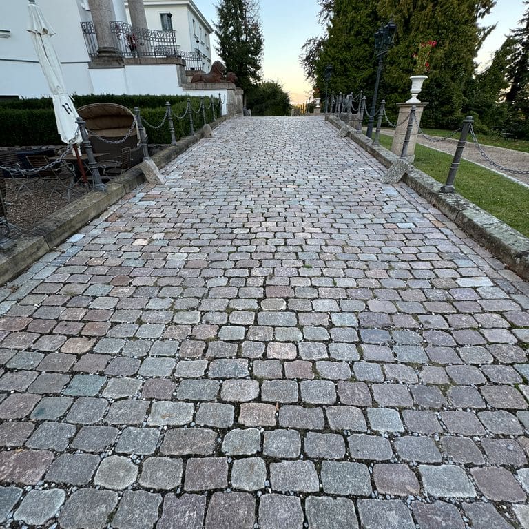Application image for Granite - Reclaimed Swedish Cobblestones. The image shows this material being used in a path pavers application. The surface finish shown is antiqued. Dominant colors shown are blue and gray. The color mix creates a cool feeling.