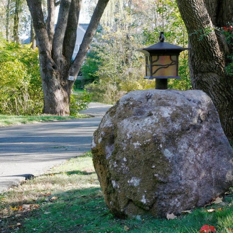 Application image for New England Fieldstone Boulders &amp; Ledgestone. The image shows this material being used for garden accents and landscape boulders &amp; ledge. The surface finish shown is weathered. The dominant color shown is gray. The color mix creates a cool feeling.