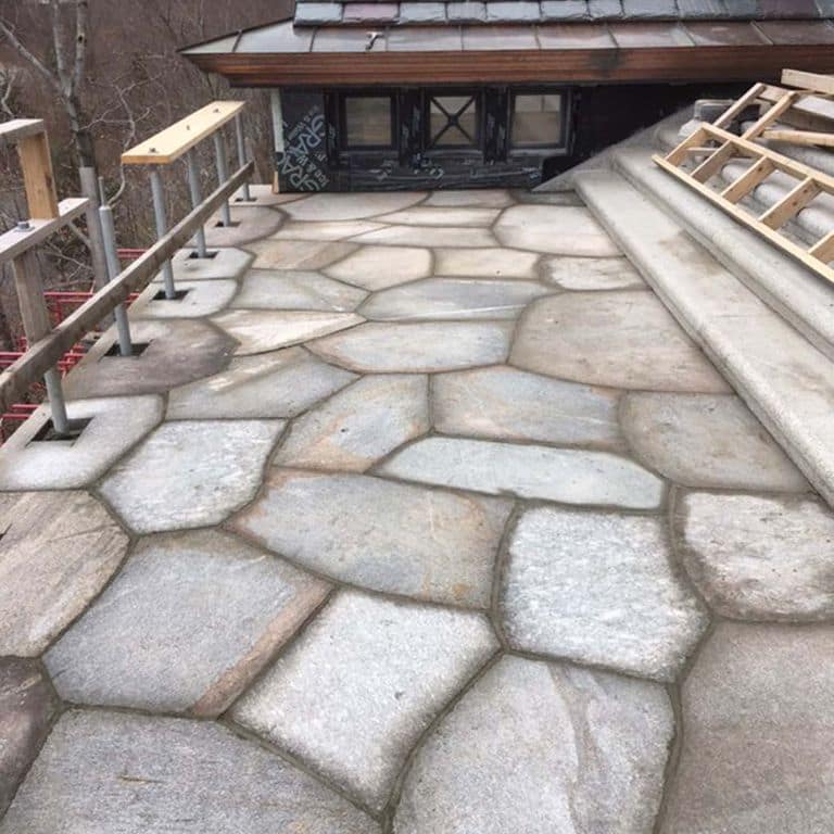 Application image for New England Fieldstone Boulders &amp; Ledgestone. The image shows this material being used in a patio pavers application. The surface finish shown is weathered. The dominant color shown is gray; with beige, blue, brown, white, tan and cream secondaries. Regular color pattern.