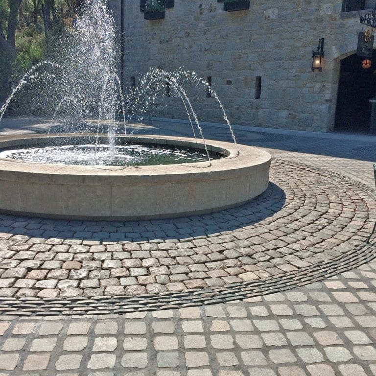 Application image for Reclaimed European Porphyry Cobblestones. The image shows this material being used in a public area application. The surface finish shown is . The dominant color shown is gray. The color mix creates a cool feeling.